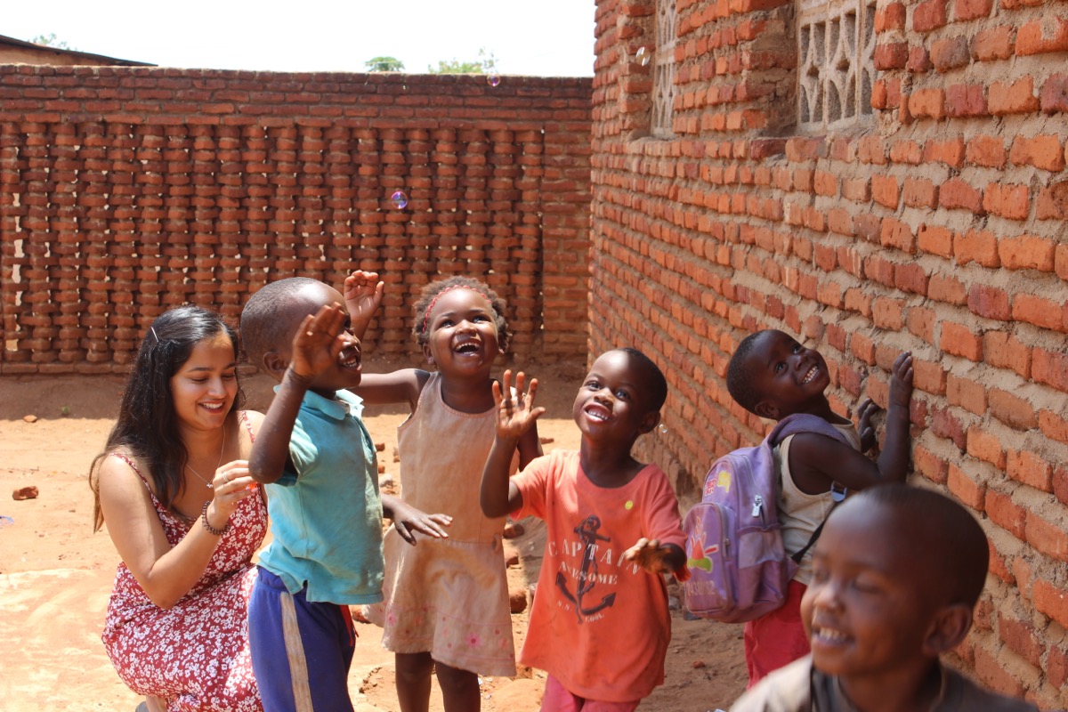 Volunteer and children laughing while chasing bubbles