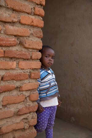 Child peeking from behind a brick wall