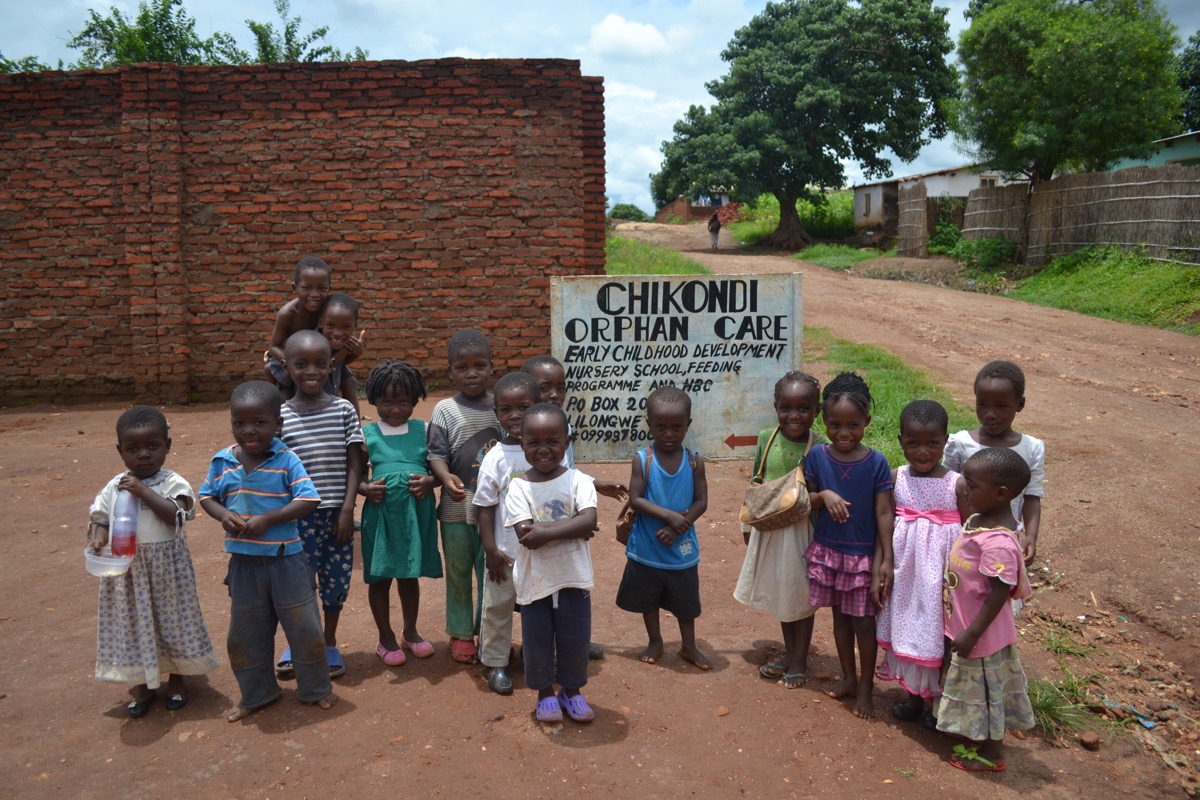 Children standing in front of the Chikondi Orphan Care sign